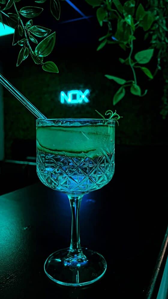 Cocktailglas bei Nacht mit Neonlicht.